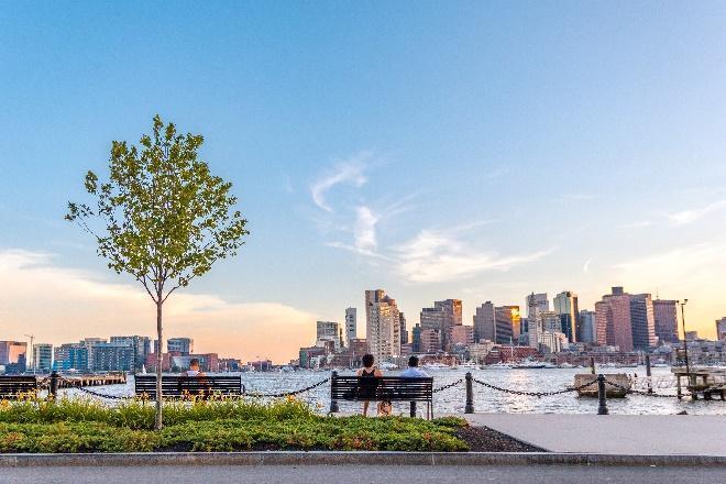 A couple sitting on a bench in front of a city

Description automatically generated with low confidence