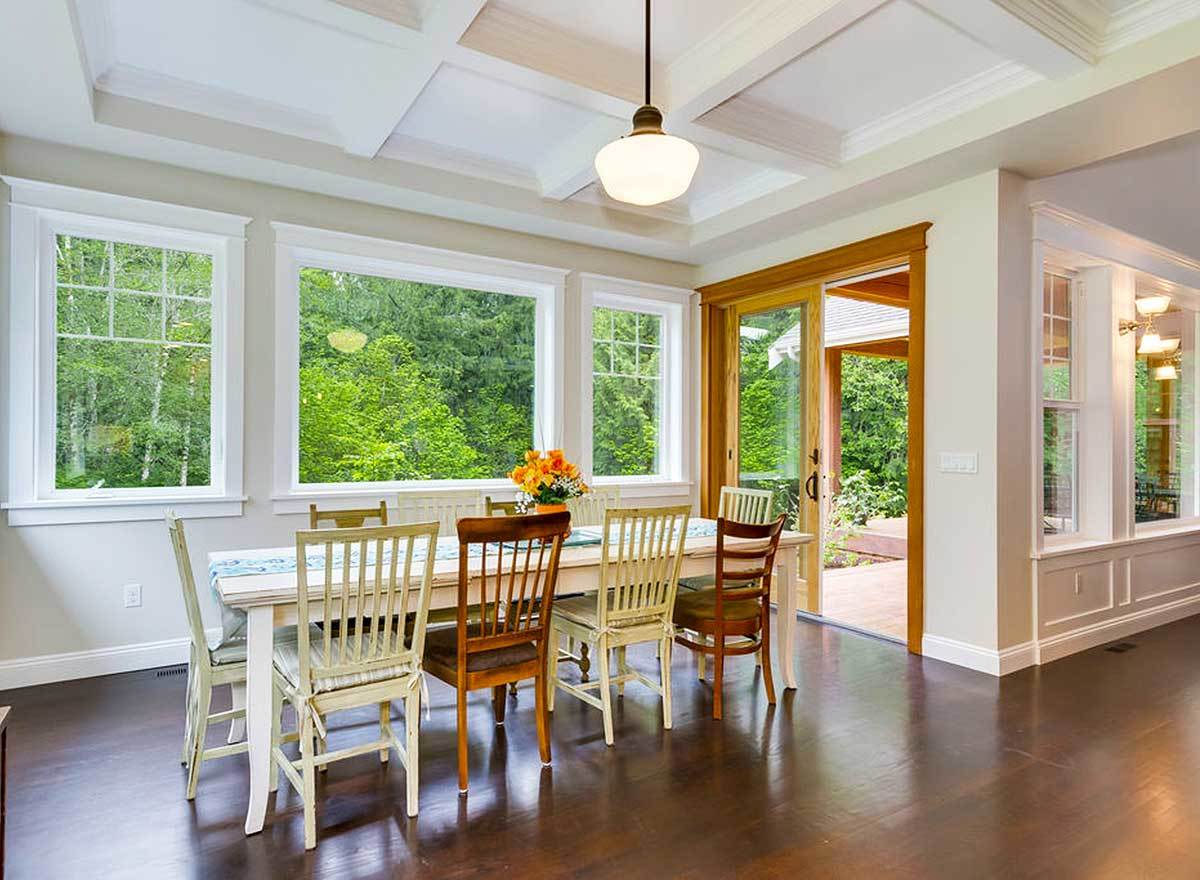 The dining room has a coffered ceiling, a rectangular dining set, and direct deck access.