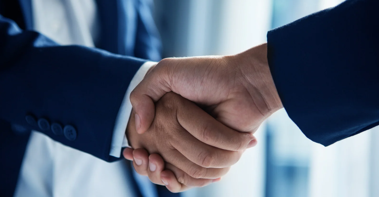(Close-up of a professional handshake between two individuals in business attire, symbolizing partnership and agreement.)
