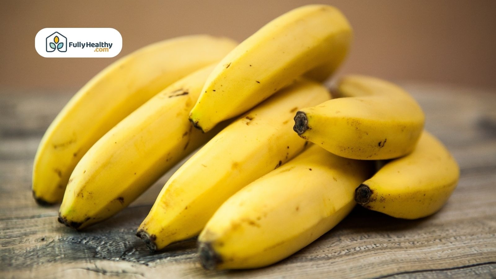 Fresh yellow bananas stacked on a wooden surface