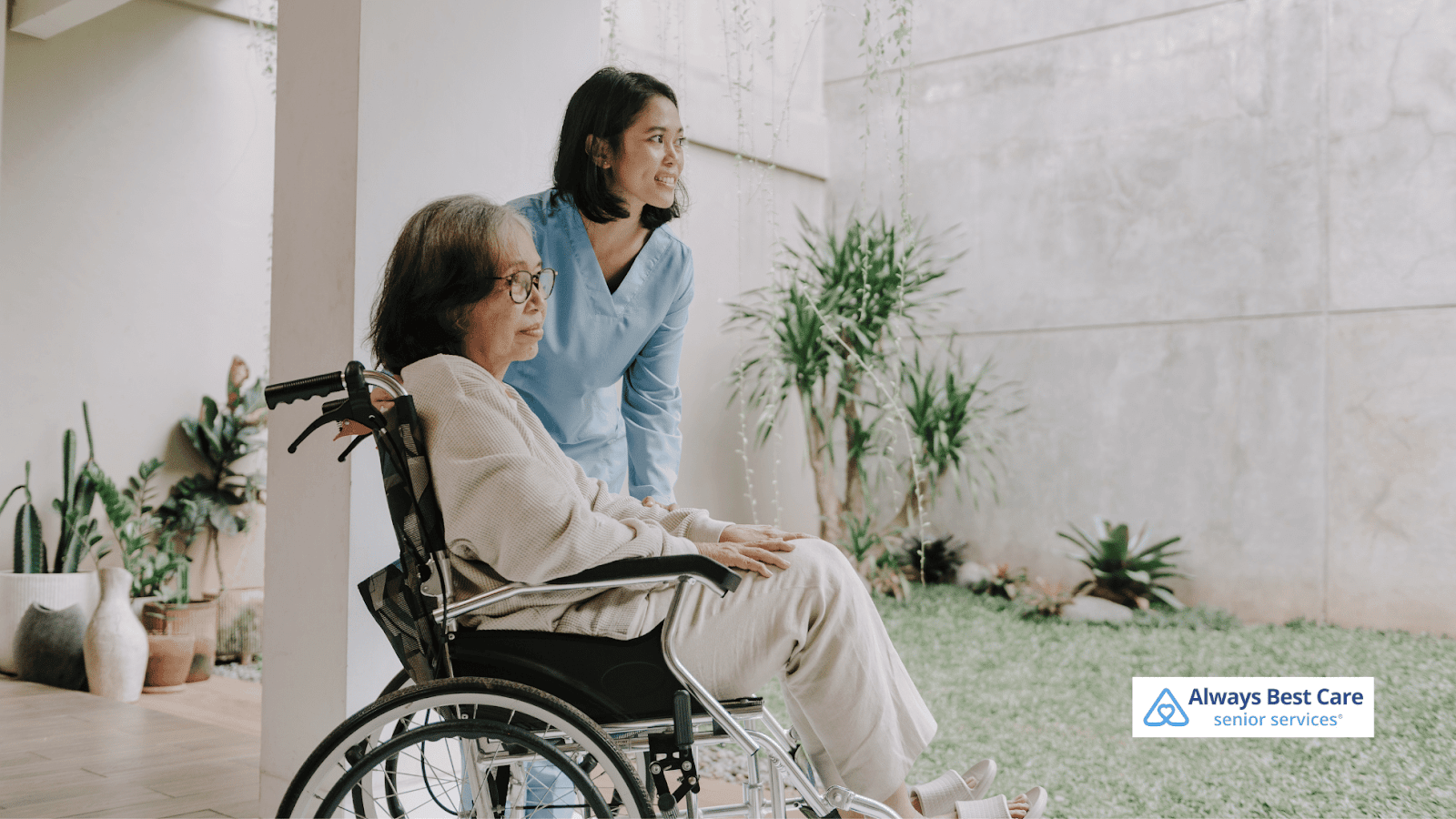 This image depicts a caregiver helping a senior woman move in a wheelchair