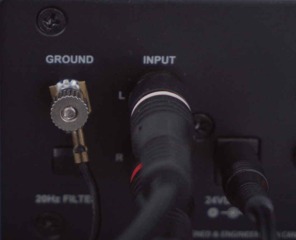 Close-up of a ground terminal and RCA input connections on audio equipment.