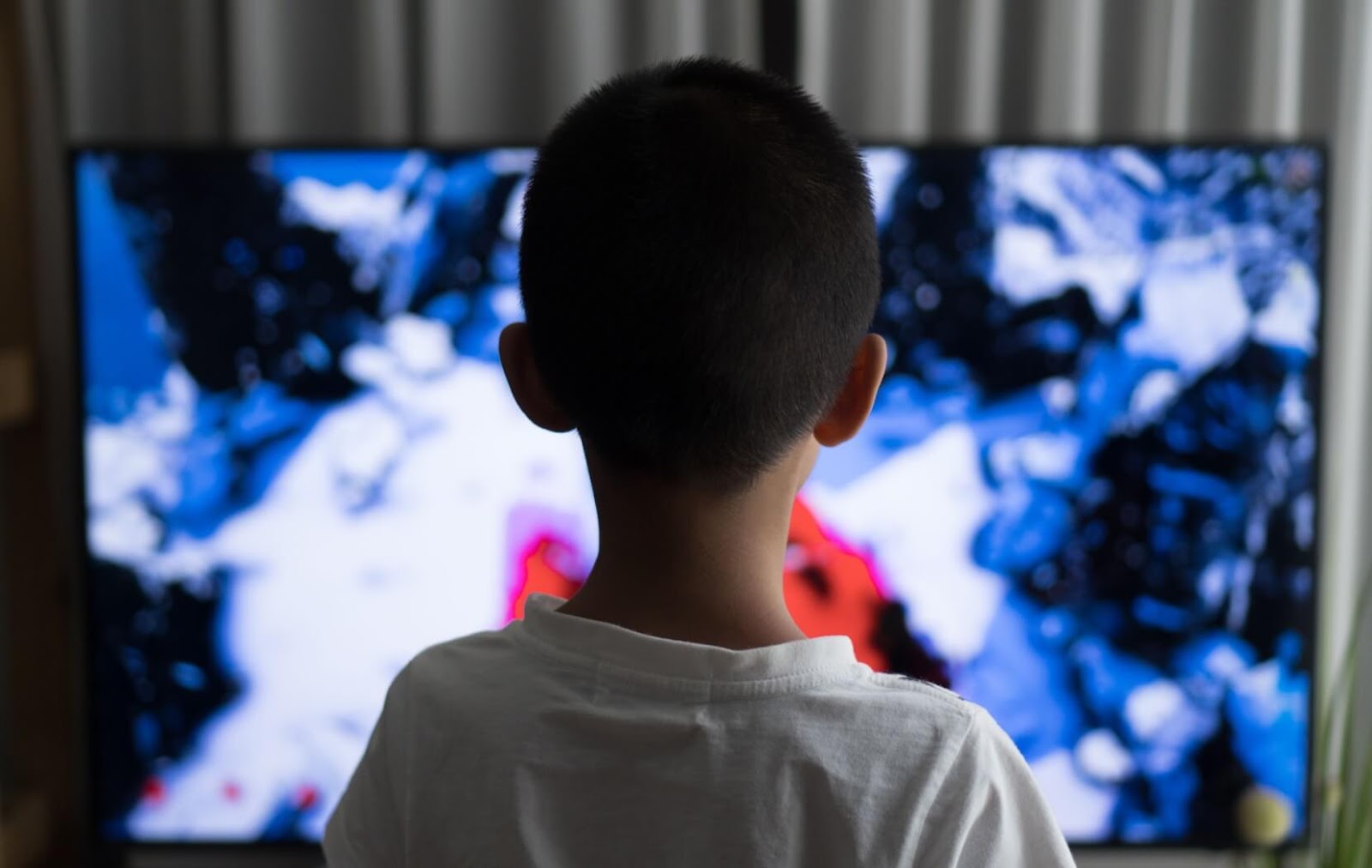 A child sits in front of a television in a dark room. It is a common myth that TV exposure damages children's eyes.