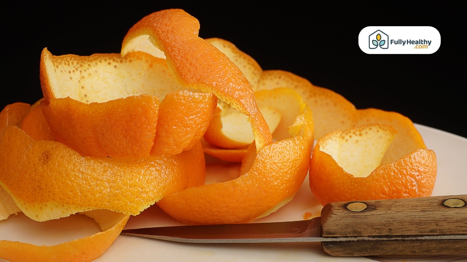 Orange peels on plate beside a knife