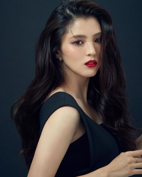 This contains an image of Han Seo Hee with long dark hair wearing a black dress and red lipstick, posing for the camera