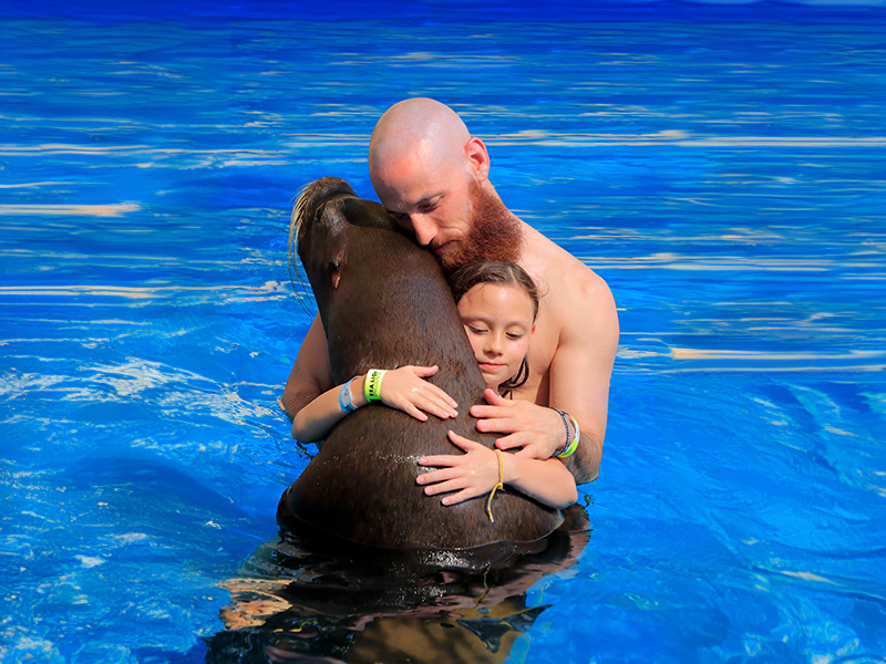 Man and girl hugging a dolphin