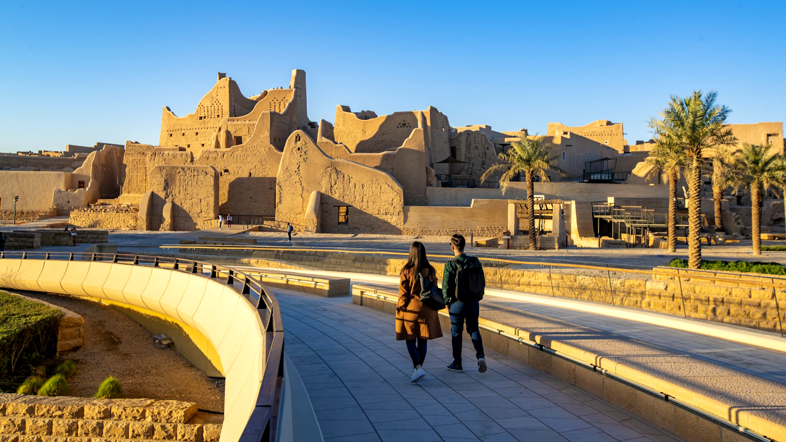 A woman wearing a long full-sleeved shirt over pants at a tourist site in Saudi Arabia - (Credits UN Tourism)