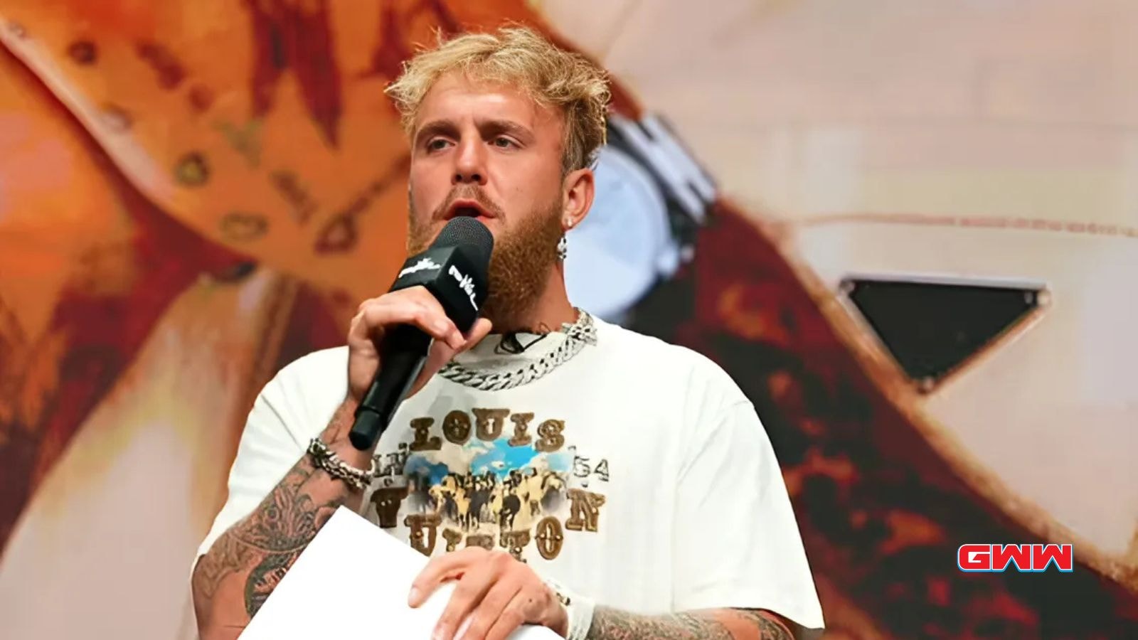 Jake Paul speaking at a press conference holding a microphone