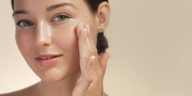 A woman is applying sunscreen and showcasing Softmaxxing skincare for youthful looks
