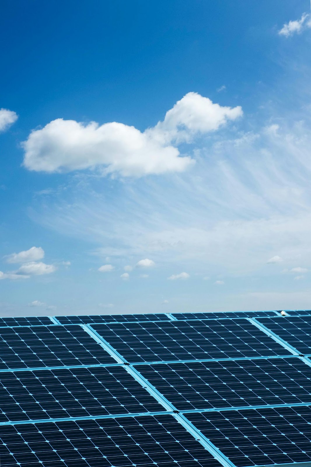 Solar panels on a metal roof on a sunny day with clouds in the sky.