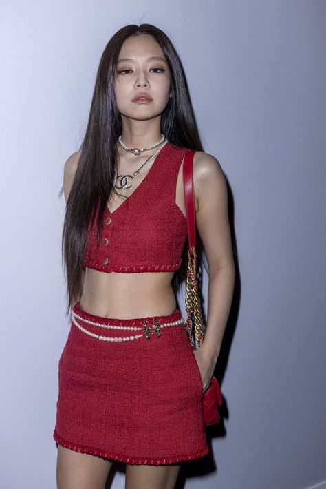 This contain Jennie  with long hair wearing a red dress and holding a handbag in front of her face