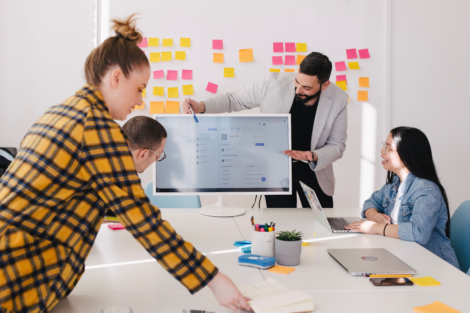 People having a meeting with a man pointing at a computer screen.