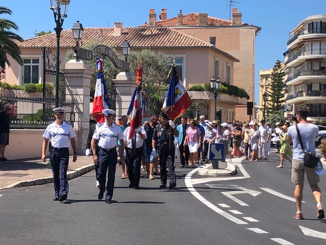 A group of people walking down a street with flags

Description automatically generated