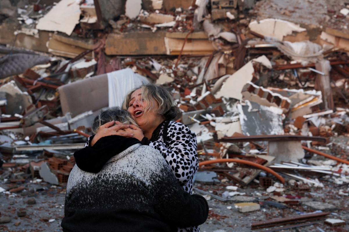 Each year,A woman embraces another person near rubble in Hatay, Turkey. Photo: Reuter