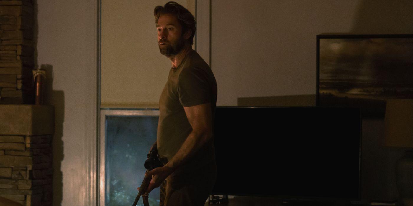 Teacup Plot- Scott Speedman wears a dark green tee and holds a gun