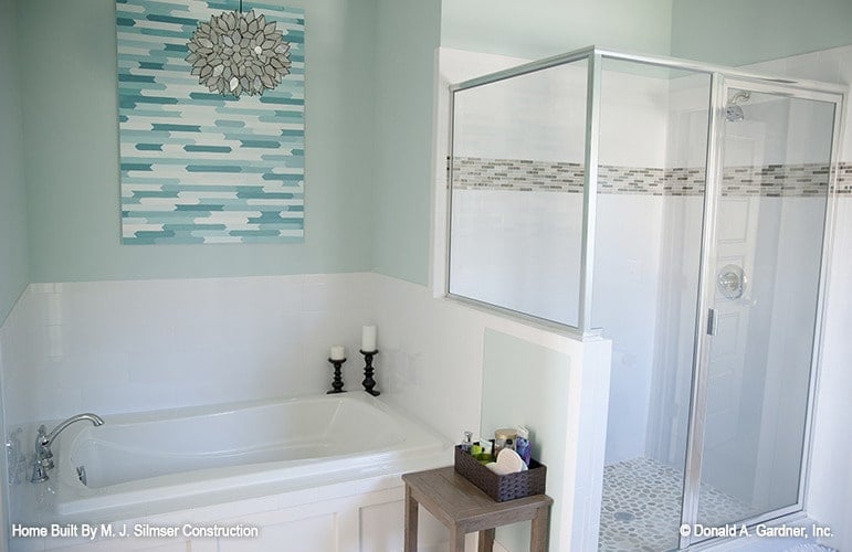 The primary bathroom offers a walk-in shower and a drop-in bathtub adorned with artwork.
