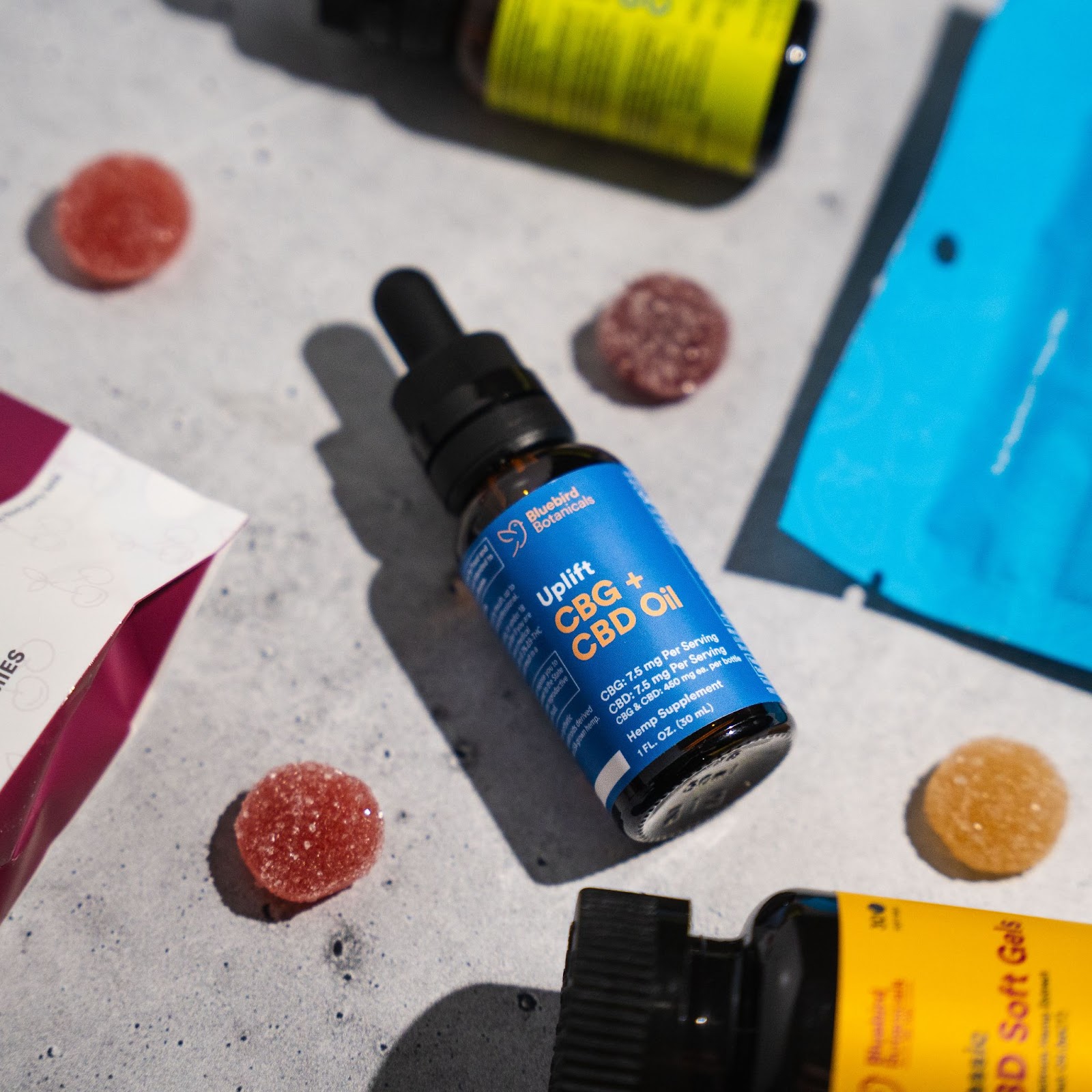 Bluebird Botanicals Uplift CBG + CBD oil, softgels, and gummies arranged together for wellness routine