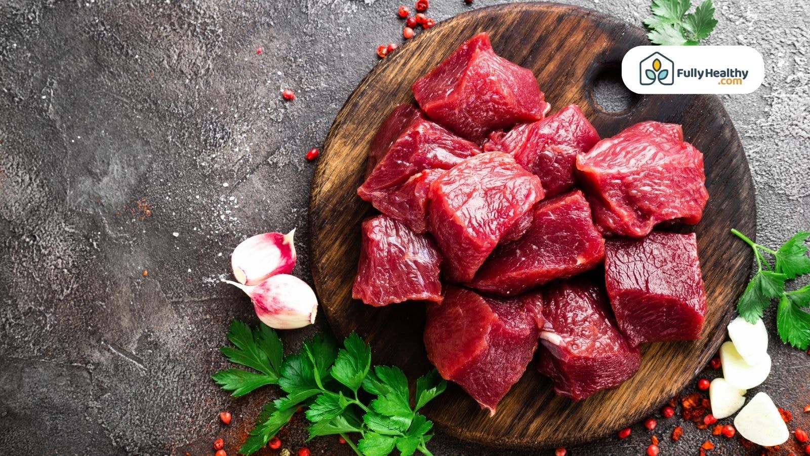 Raw beef chunks on wooden board with garlic and fresh parsley