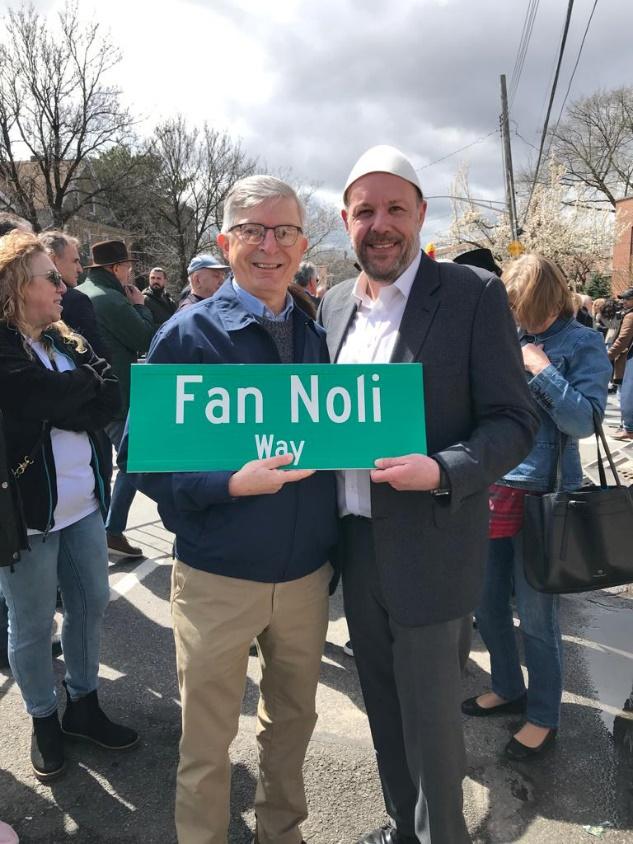 Two men holding a sign

Description automatically generated