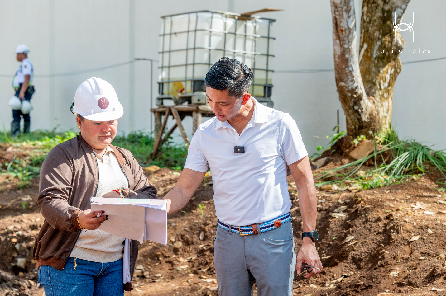 A person in a hard hat holding a paper

Description automatically generated