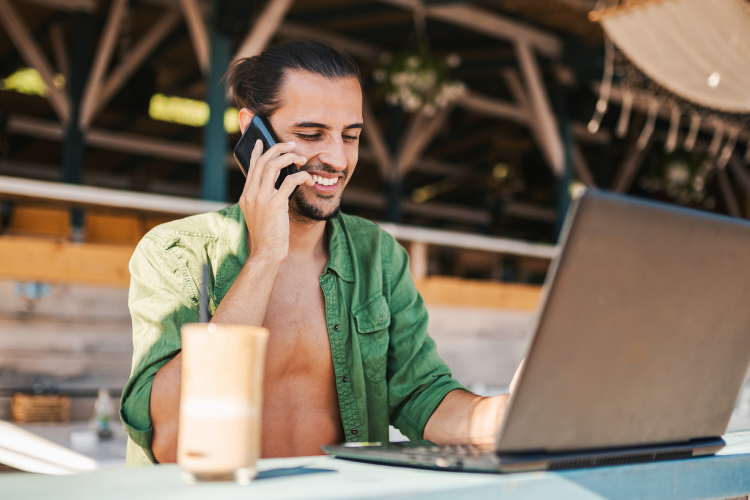 man watching football on his laptop smiling talking on the phone