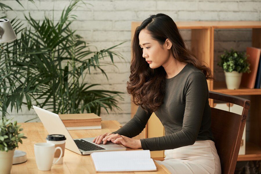 A person sitting at a desk using a computer  Description automatically generated