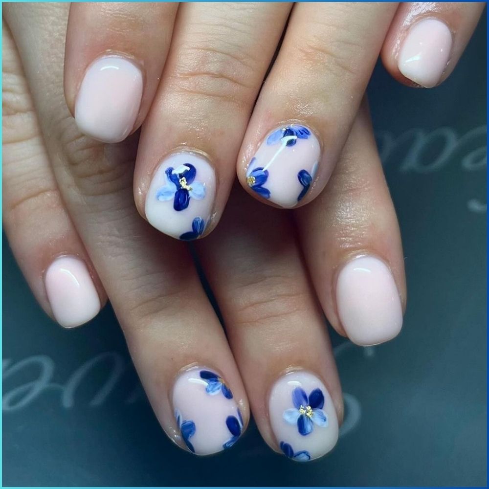 Close up of hands with flowered designed blue nails having Bluebells and Blossoms