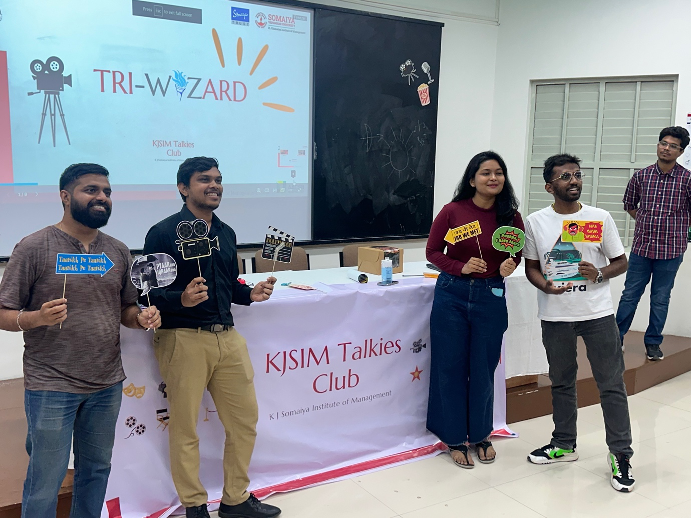 A group of people standing in front of a table with signs

Description automatically generated