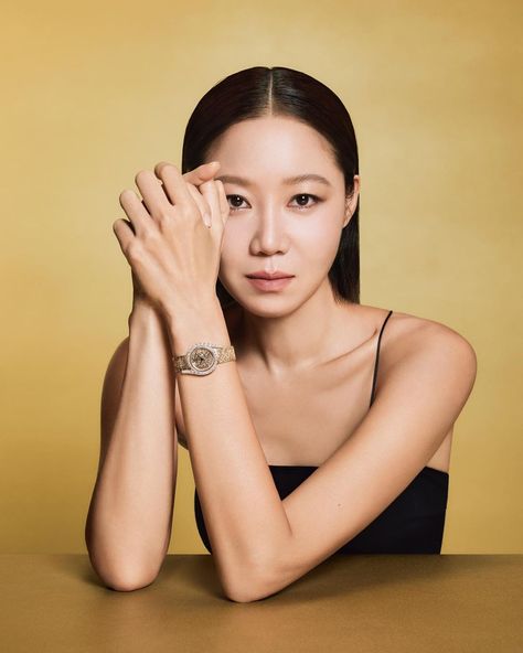 This contain Actress Gong Hyo Jin  sitting at a table with her hands on her face and looking off to the side