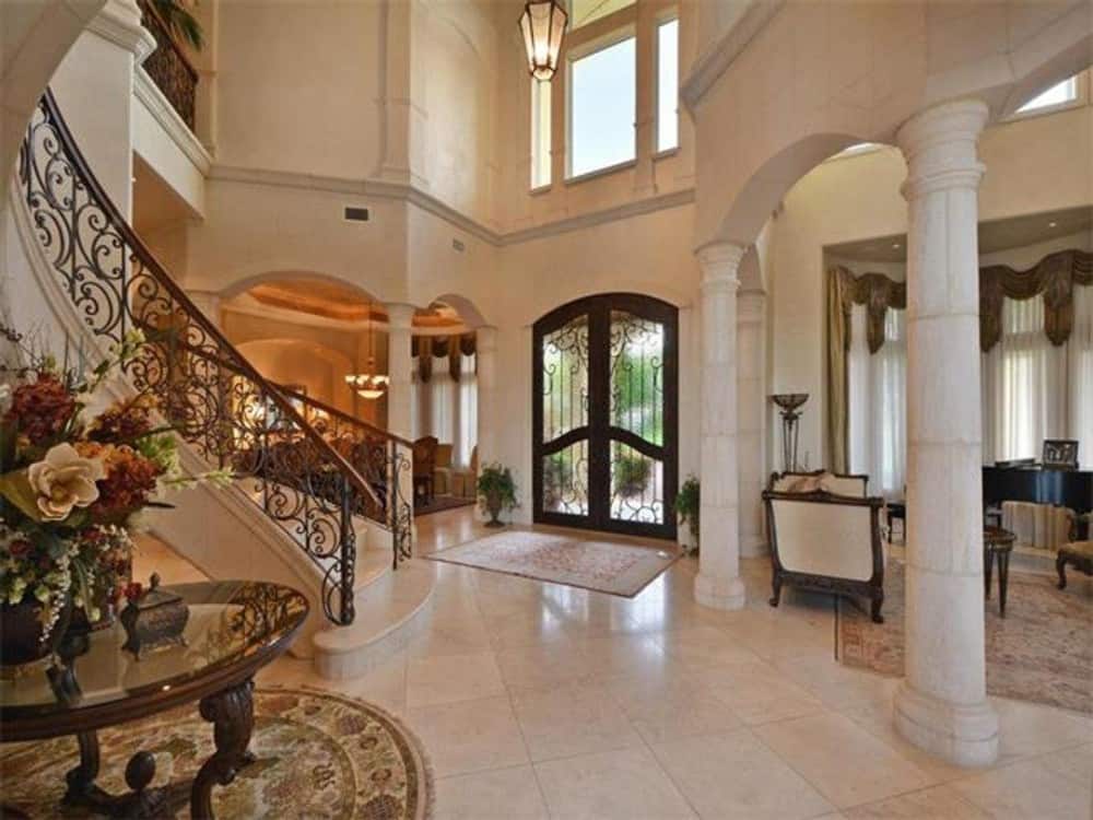 Foyer with a french entry door, a two-story ceiling, and clerestory windows. It is flanked by the formal dining and living rooms framed with arches.