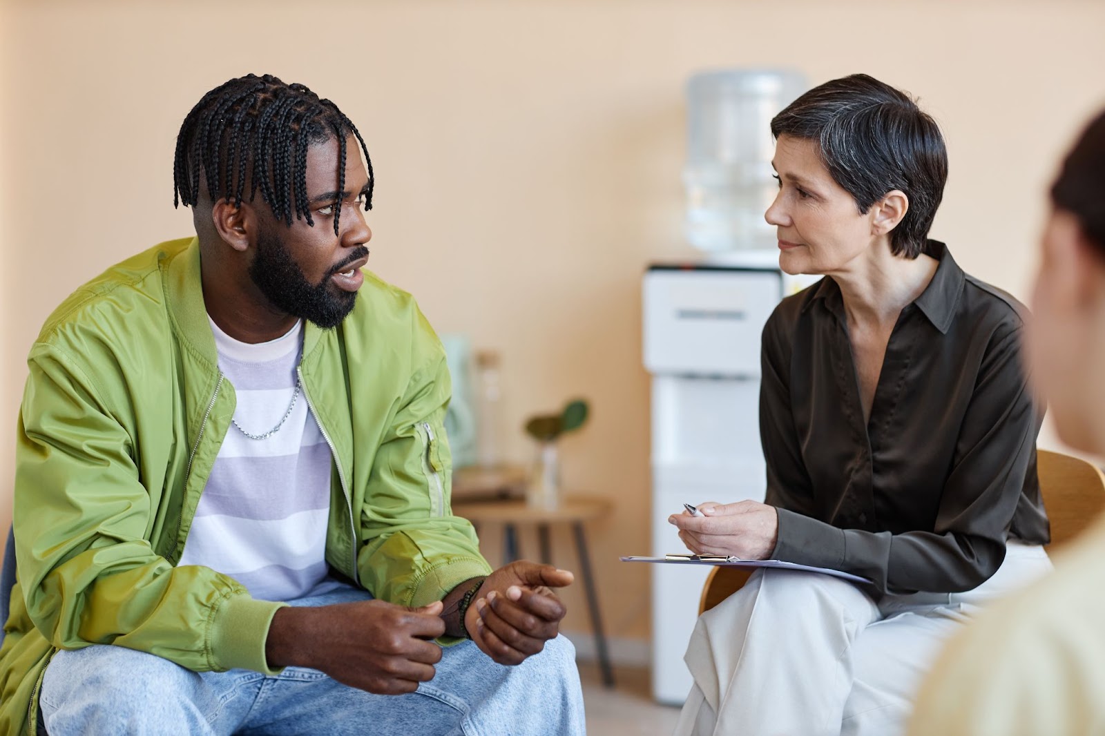 Man sitting beside a female psychologist with a water cooler in the background.