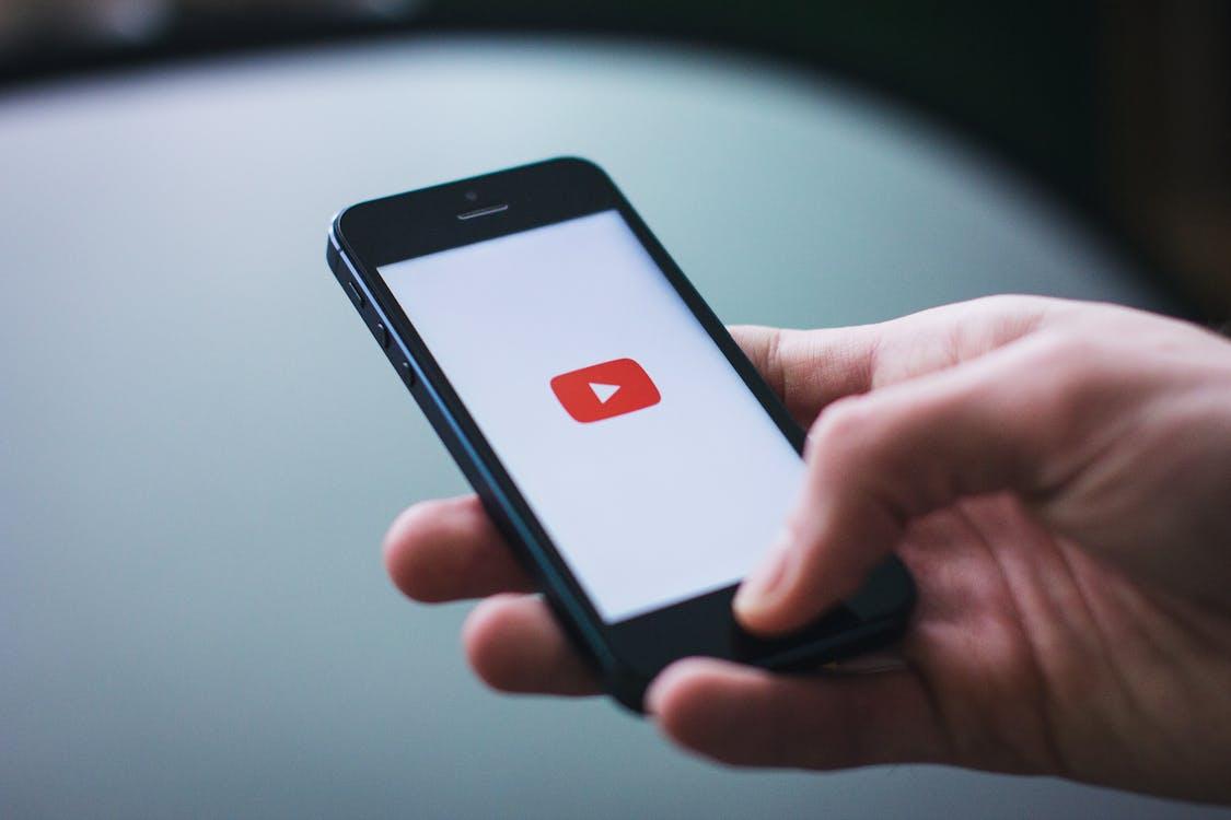 Free Close-up of a hand holding a smartphone displaying the YouTube app on the screen. Stock Photo