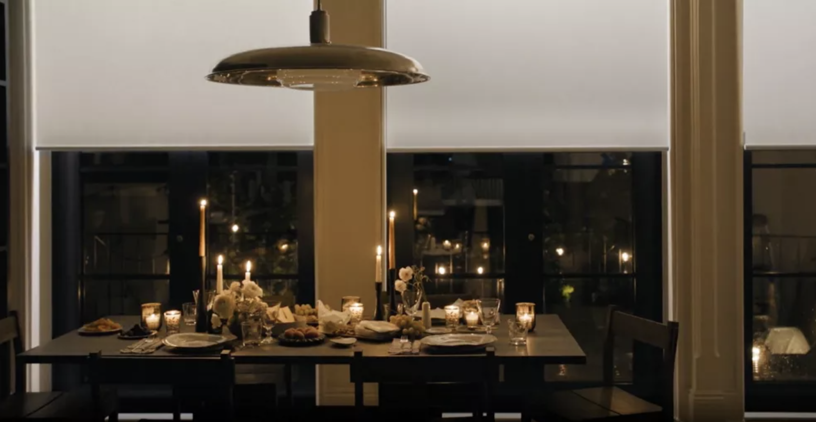 Aura® Illuminated Shades frmo hunter douglas over large picture windows in the dining room of a dining room with a table set for dinner