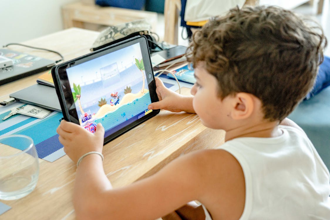 Free A Boy in White Tank Top Playing on a Tablet Stock Photo