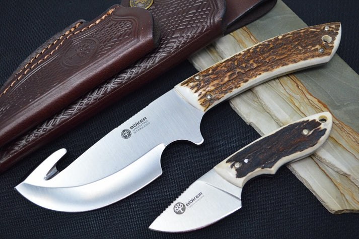 An image showing the Boker Arbolito Guide combo fixed blade set, which includes a caper knife and a gut hook knife. The knives feature 440C stainless steel and stag handles.