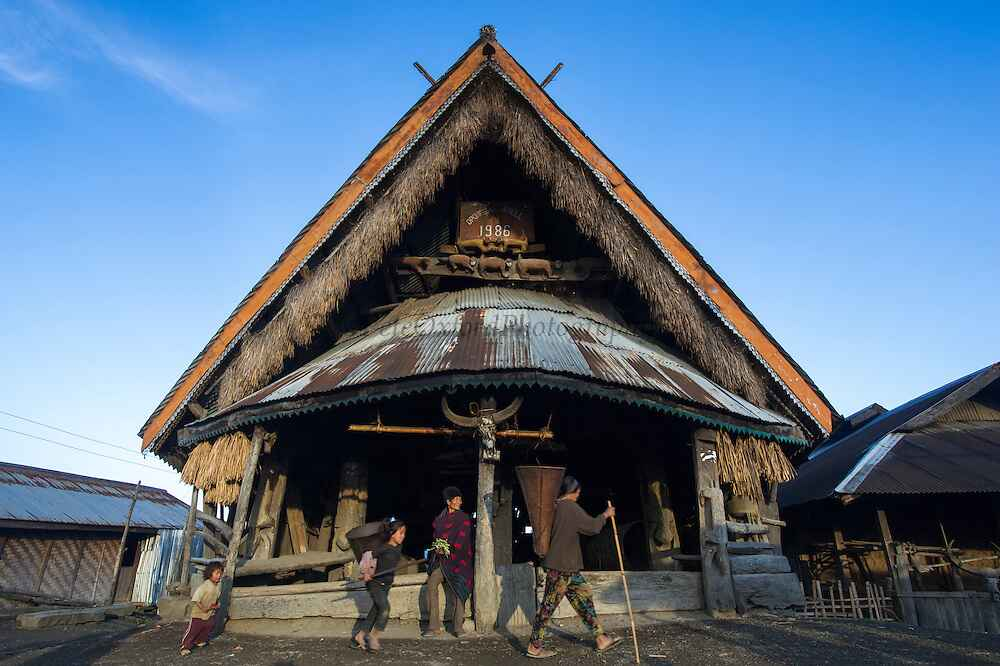 Traditional Naga house with a thatched roof, dated 1886, in a rural setting.