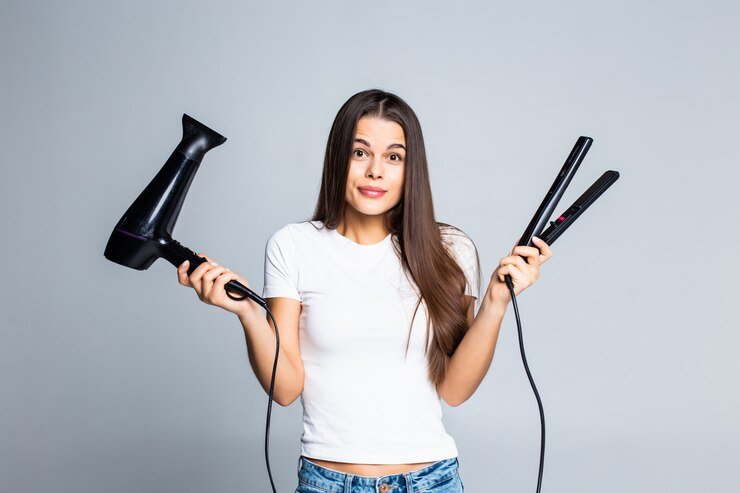 Young pretty woman holding hair dryer and straightener