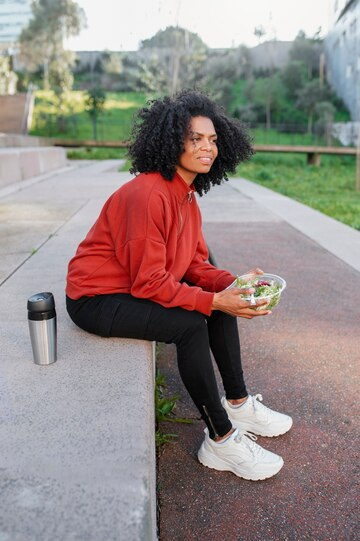 Person sitting outside with a salad and thermos