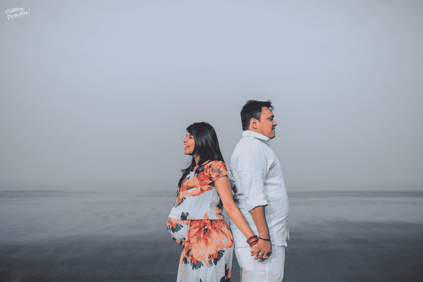 Pre wedding shoot of a couple in Suvali Beach holding hands and standing in opposite directions.