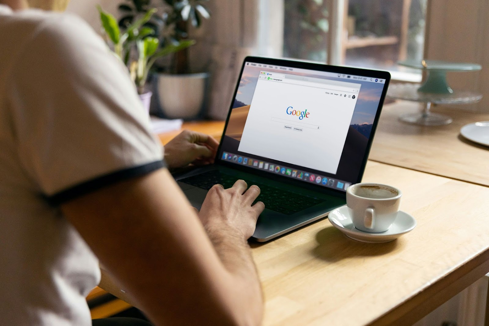 A man is using a laptop showing the Google homepage with google forms crypto scam