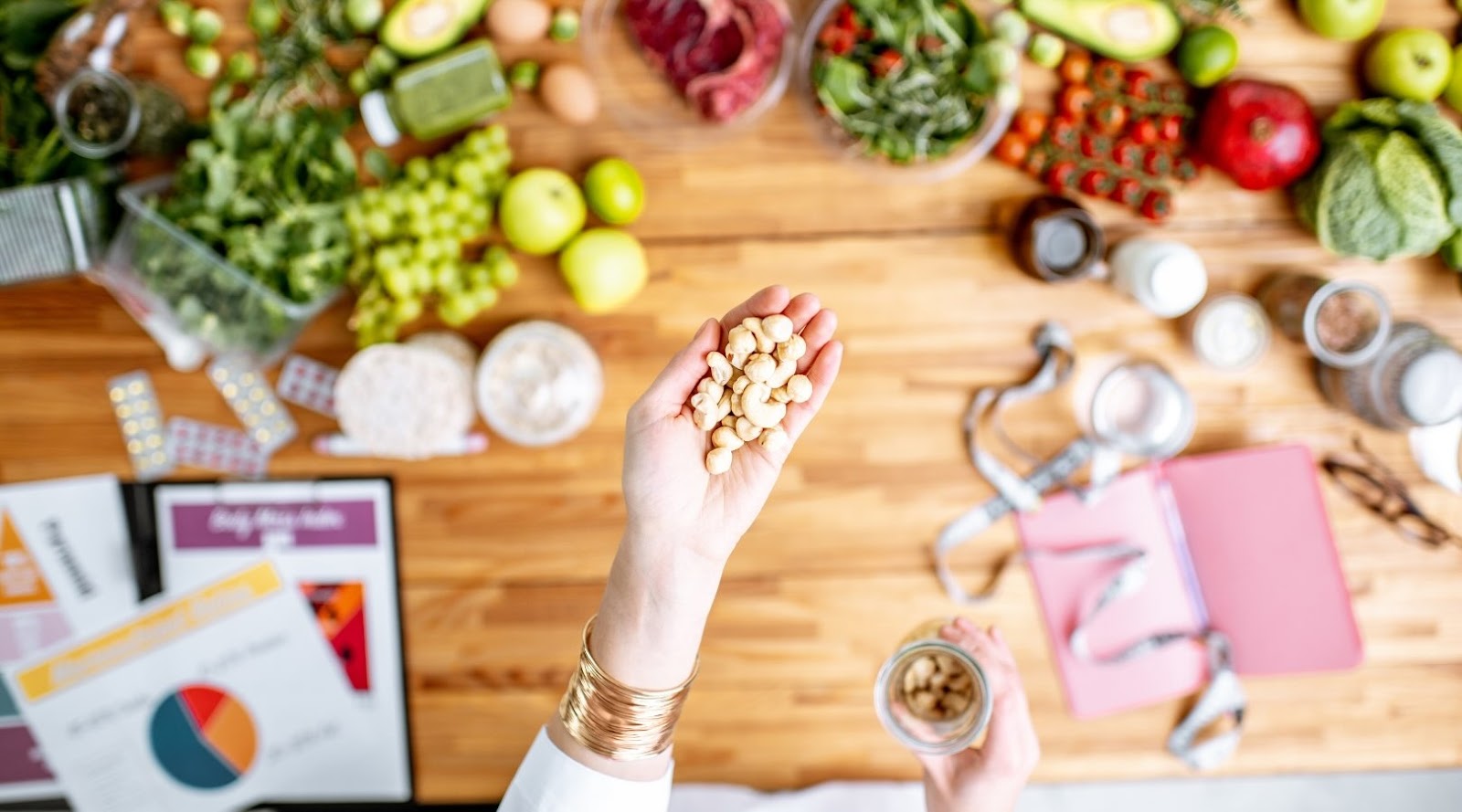 Registered Dietician Nutritionist holding nuts in her hand above a counter top full of healthy food.