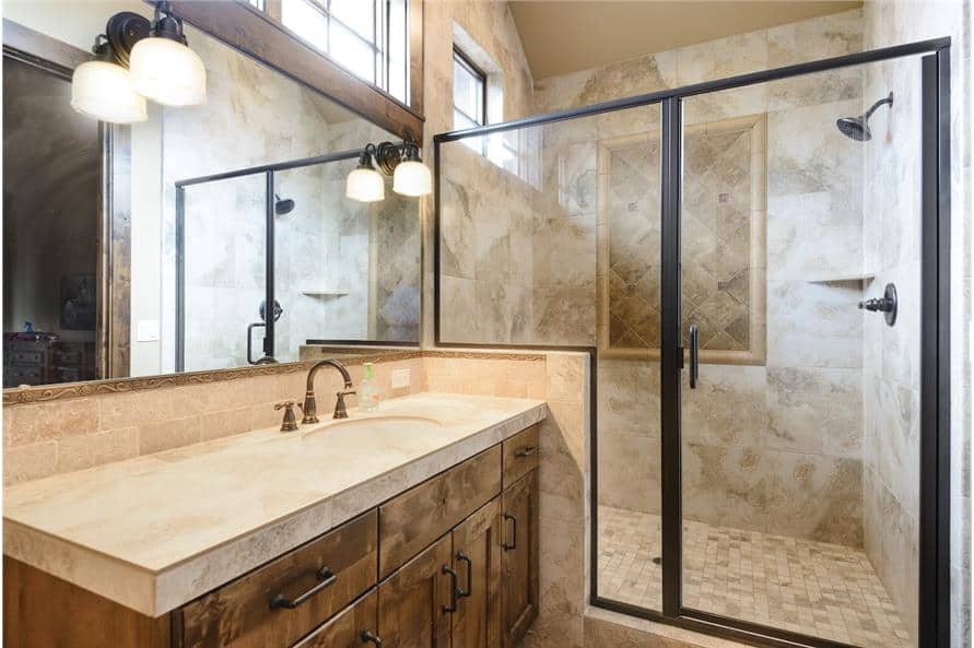 Bathroom with single sink vanity and a walk-in shower enclosed in a glass-hinged door.