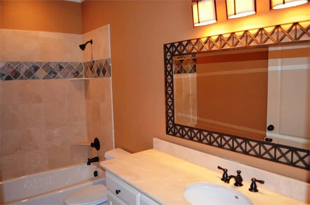 Bathroom with sink vanity and a tub and shower combo fitted with wrought iron fixtures.