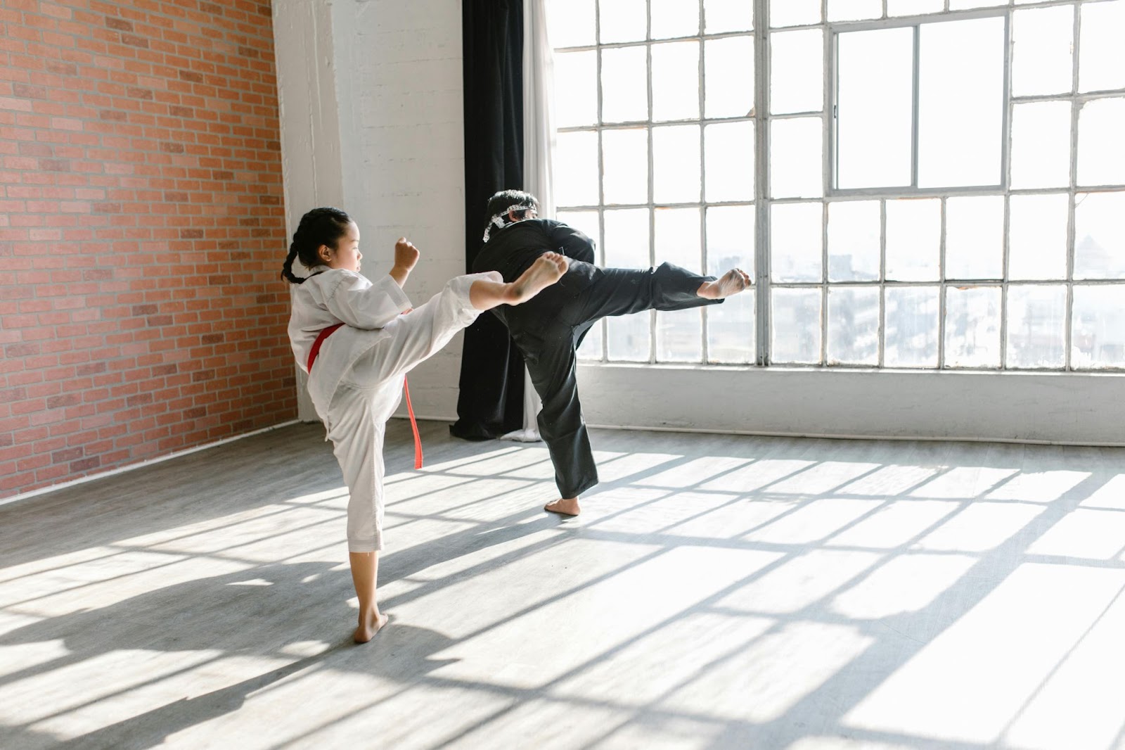 A martial arts instructor teaching a young student how to kick