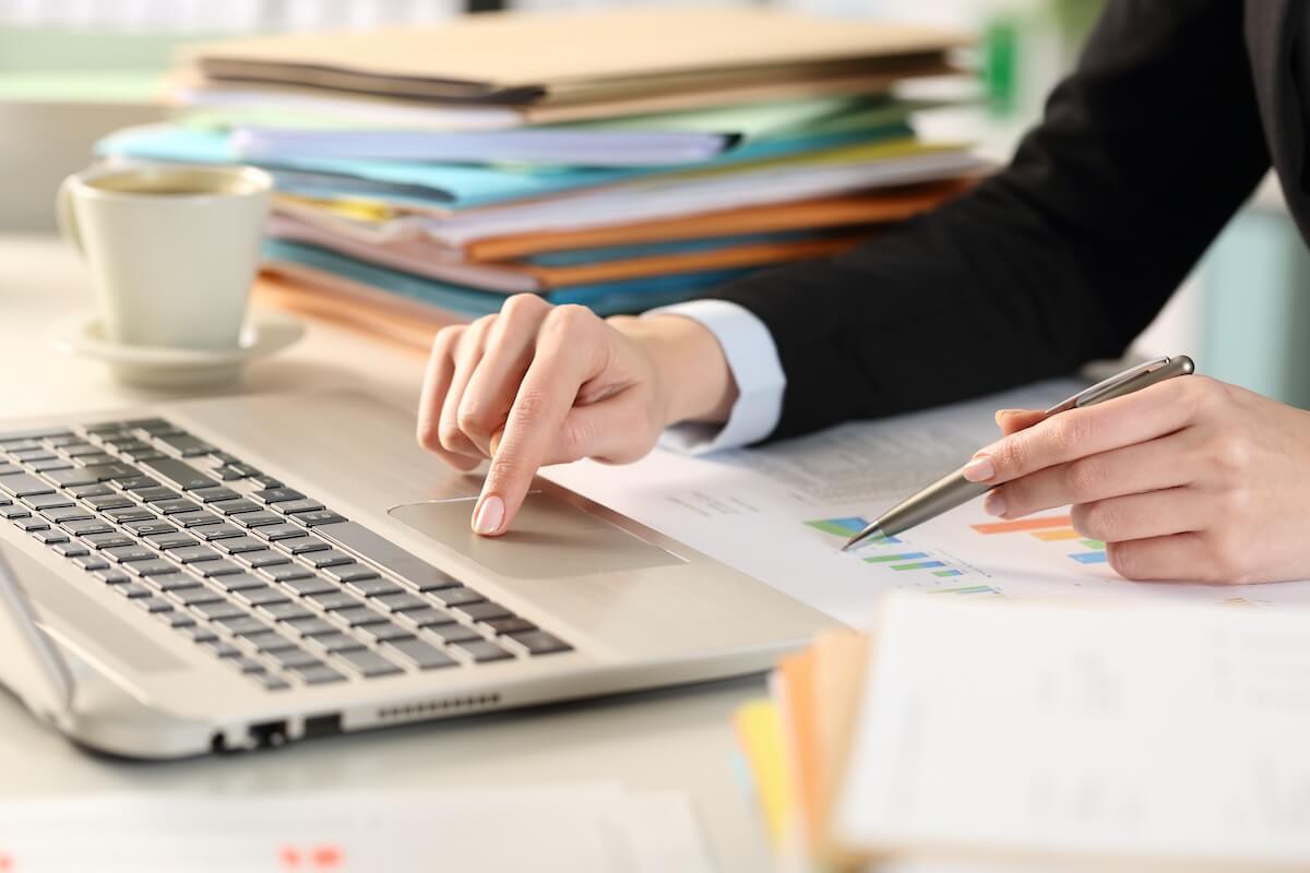 Payroll management process: employee using a laptop while holding a pen