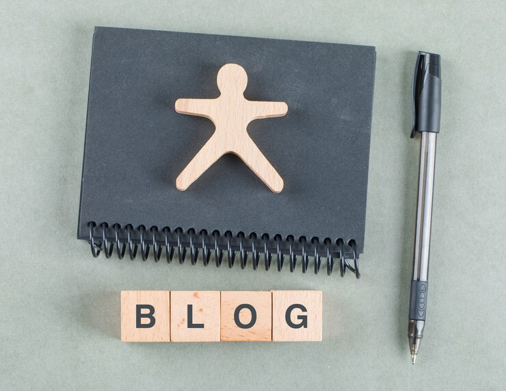 Depiction of blog entry concept with wooden blocks, pen and black notebook 