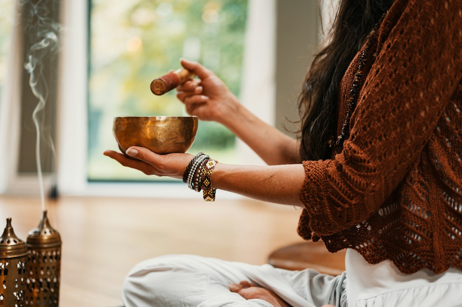 A woman sits peacefully, meditating with a warm bowl in her hands, surrounded by a calming atmosphere.