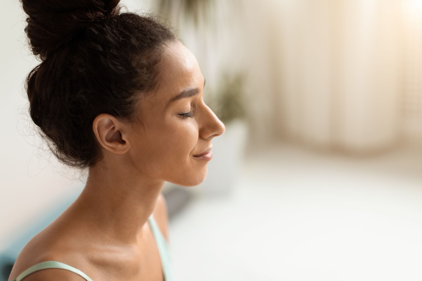 Woman with her hair in a bun and her eyes closed. 