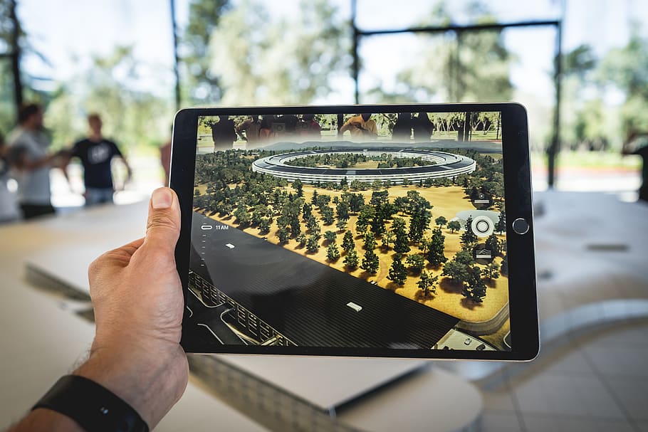 Person holding an iPad with AR overlay of a model city