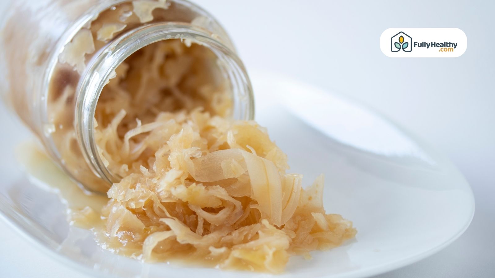 Jar of sauerkraut spilled on white plate showing juicy texture